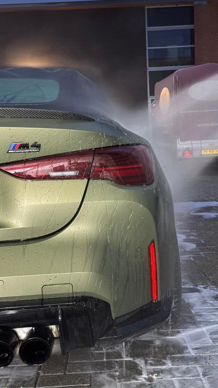 BMW M4 wordt buiten met de hogedrukreiniger voorgewassen